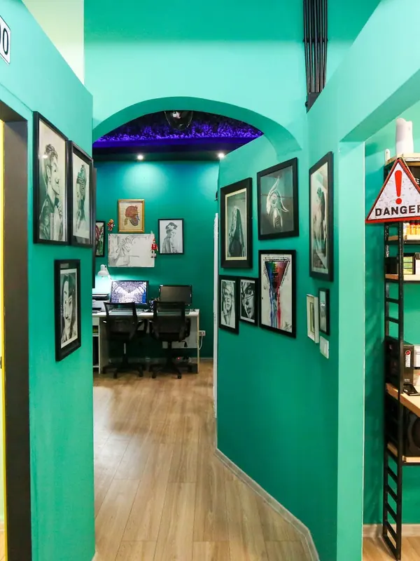 A corridor of framed artwork leading to the tattoo rooms
