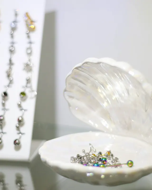 Piercing jewellery on display beside a pearl shell dish